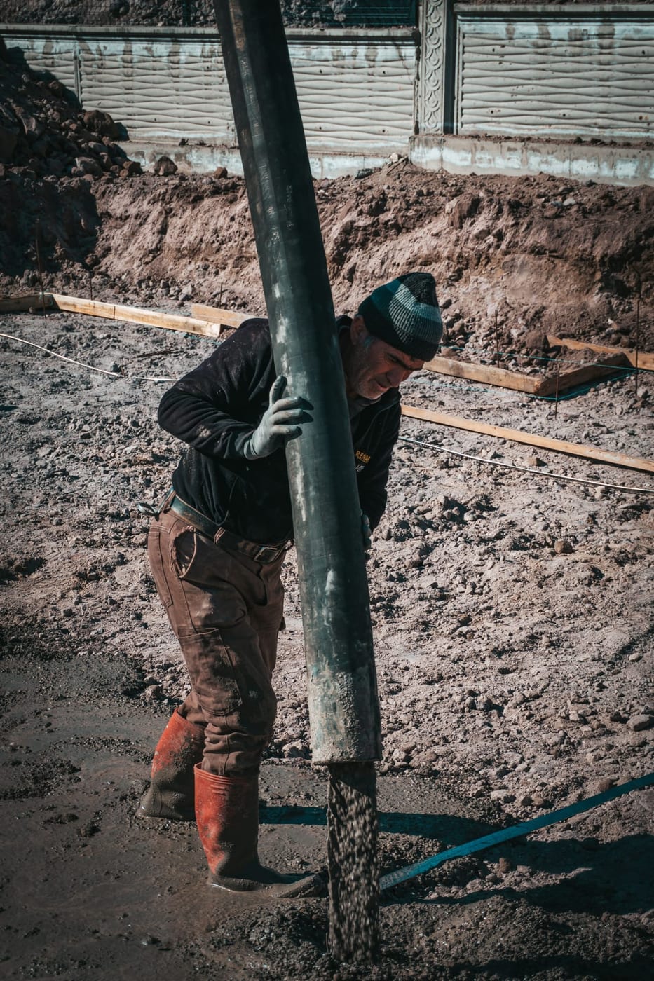 Estrichleger führt den Schlauch einer Betonpumpe über eine Bodenplatte