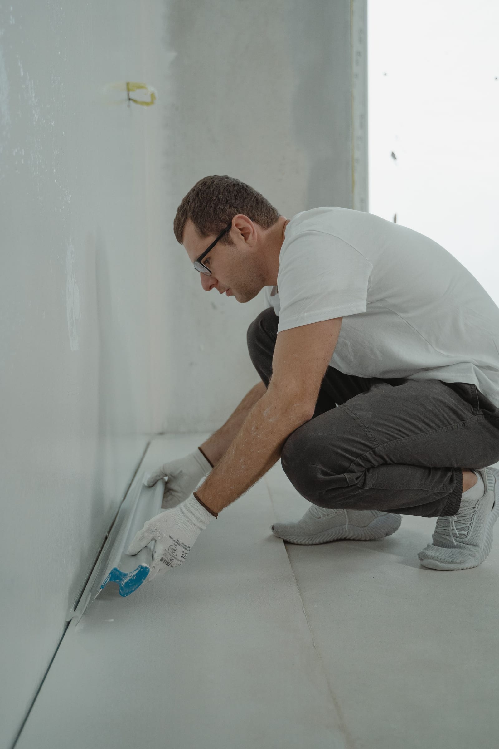 Estrichleger bringt den Randdämmstreifen an der Wand an, bevor der Estrich eingebracht wird
